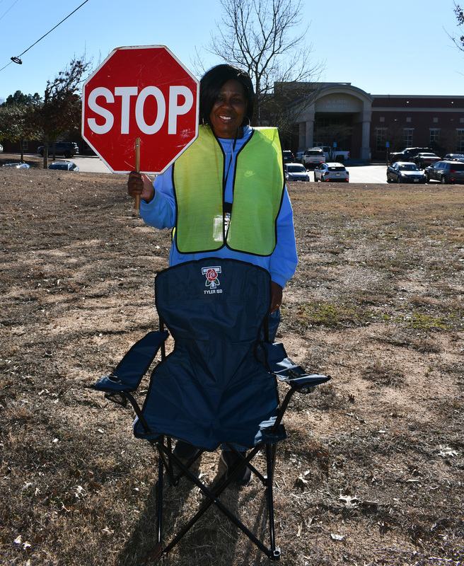 woman wearing yellow vest holding stop sign