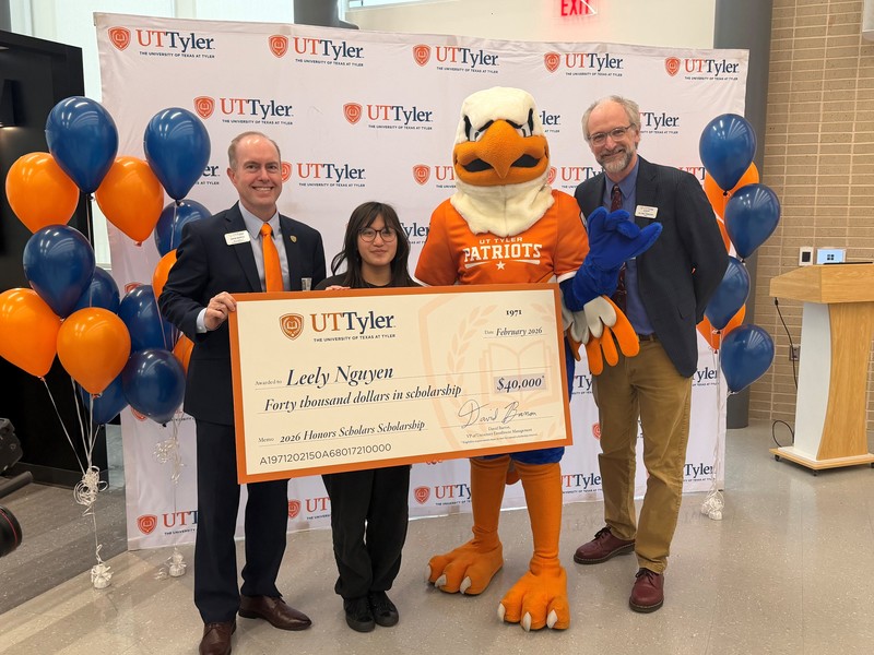 two men, teen girl, and Eagle mascot holding giant check