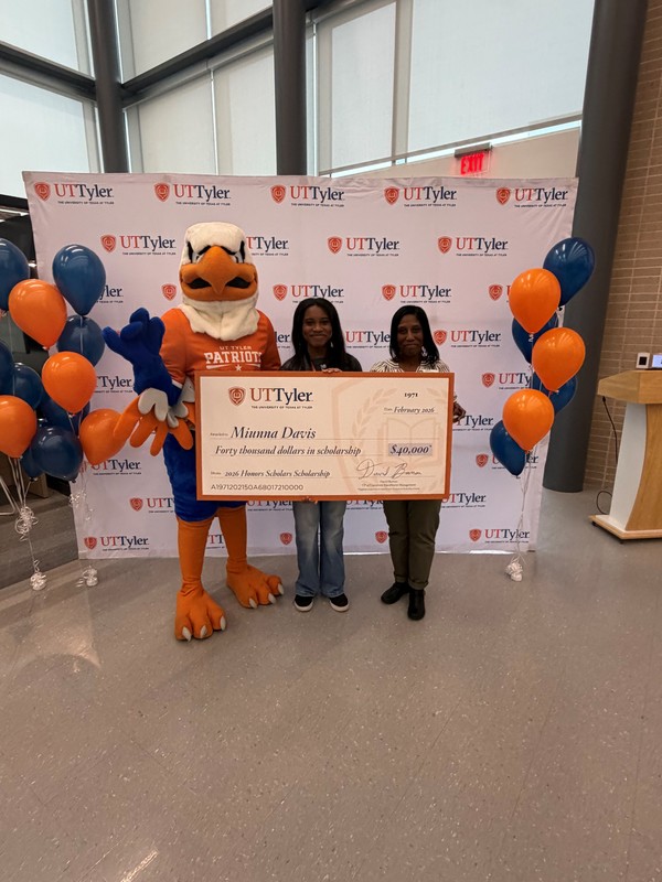 Eagle mascot and two women holding giant check