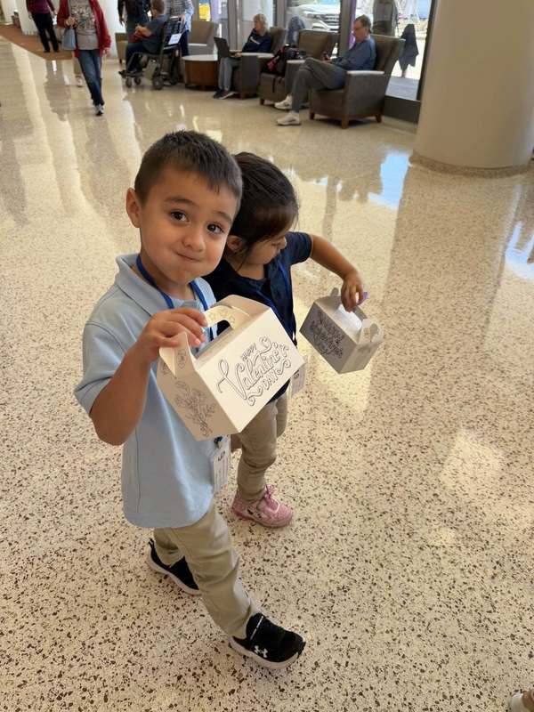 young children walking down hall with Valentine box