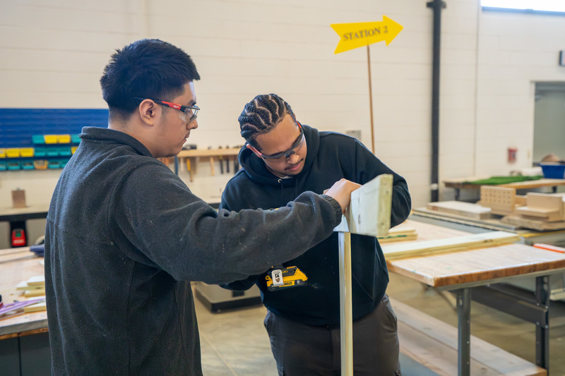 two teen boys working to screw two boards together