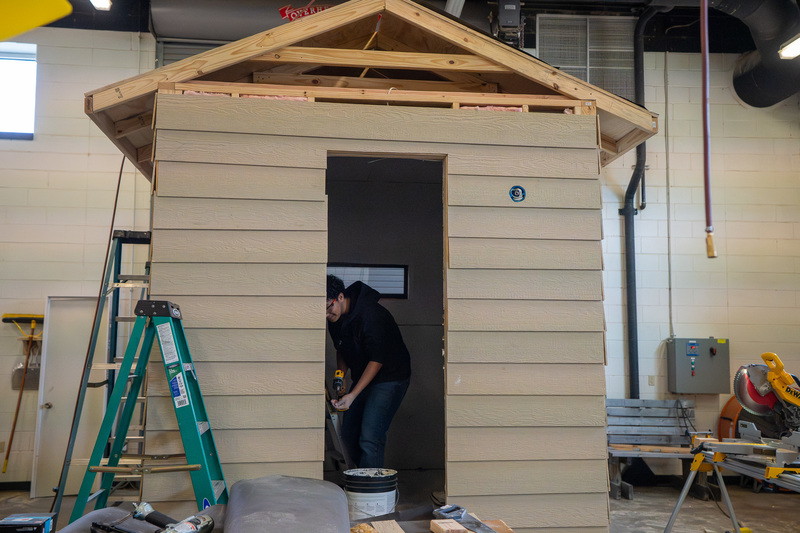 teen boy working inside shed he is building
