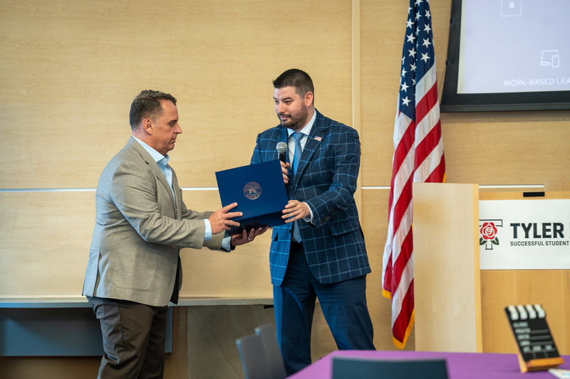 man handing another man a certificate