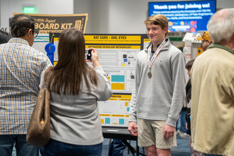woman taking picture of teen boy wearing medal