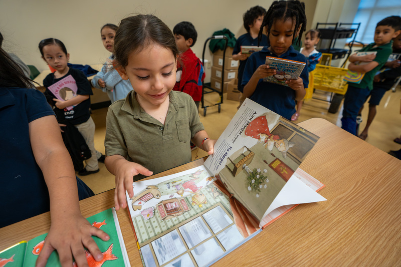 young child reading book in classroom