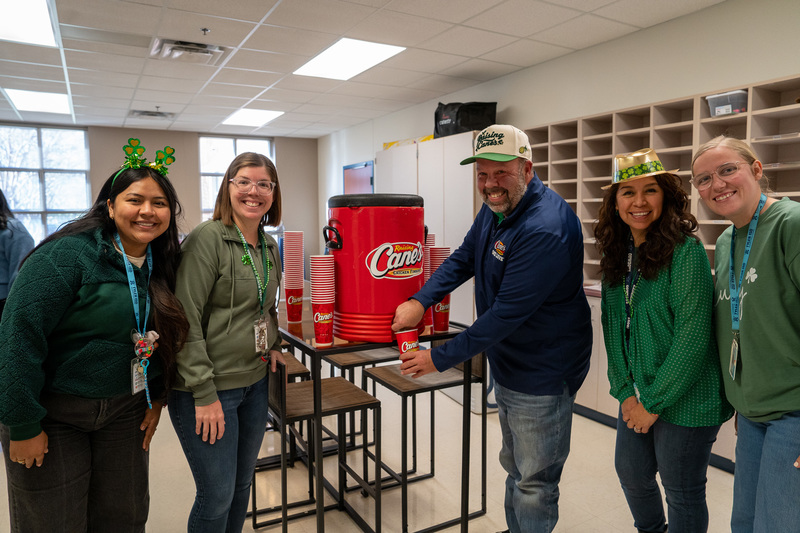 man and woman standing in break room with man pouring drink out of cooler