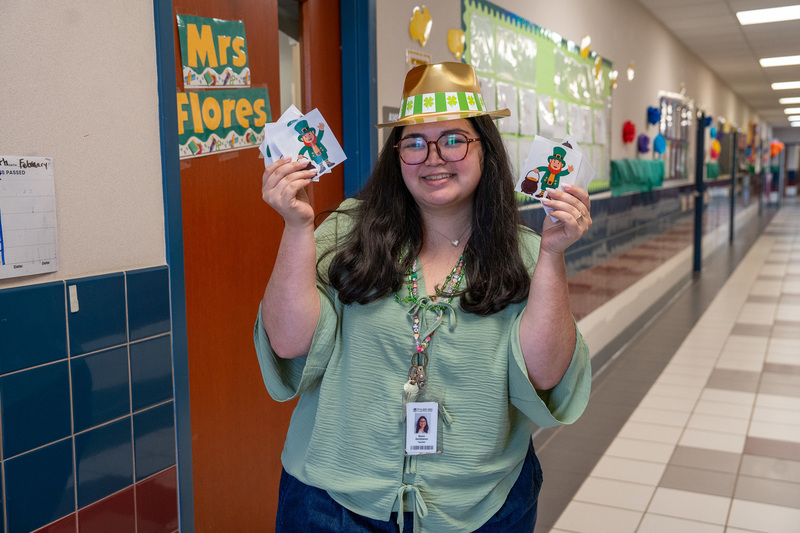 woman holding cards with leprechauns on them.