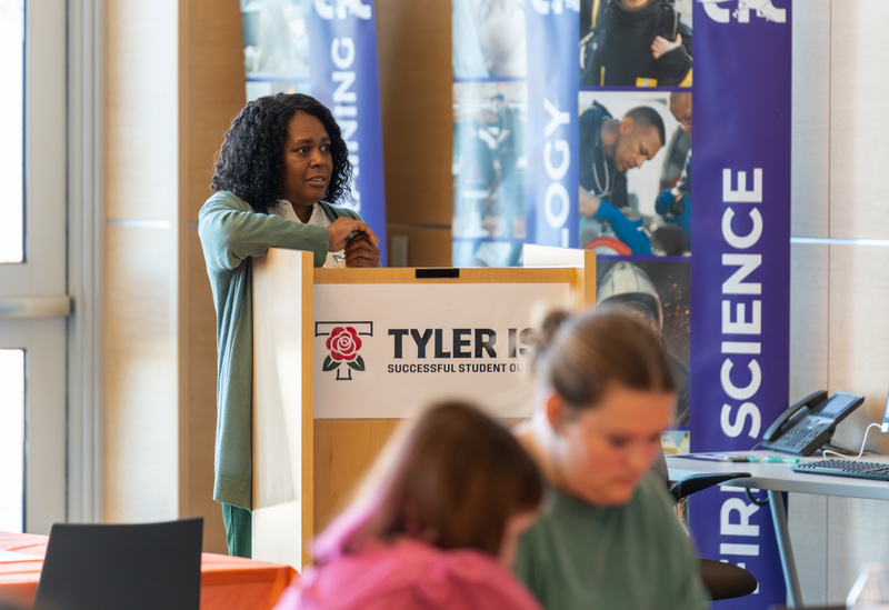 woman at podium talking to teens