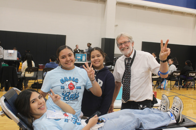 three teens and a man making the "peace" sign with their hands