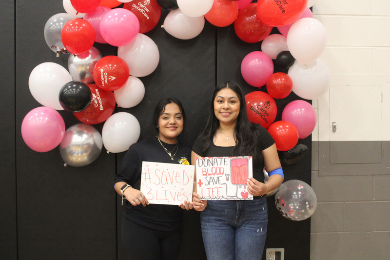 two teen girls holding signs saying they donated blood
