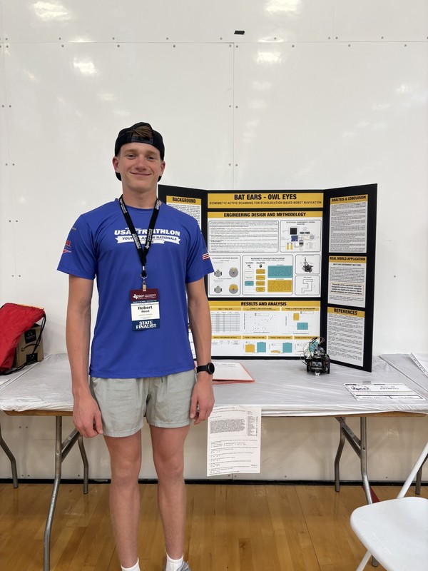 teen boy standing in front of trifold board on a table