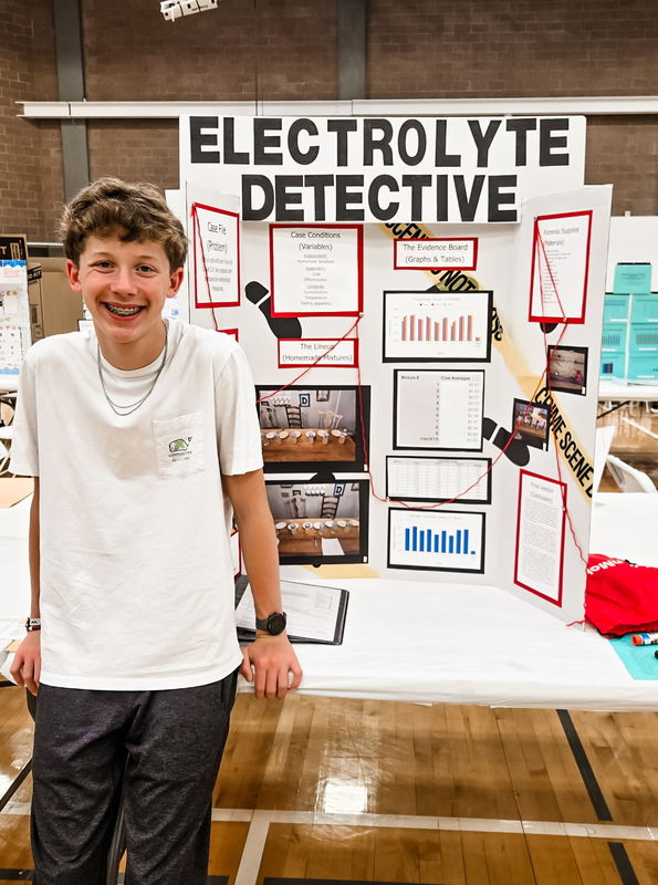 teen boy standing in front of trifold board on a table
