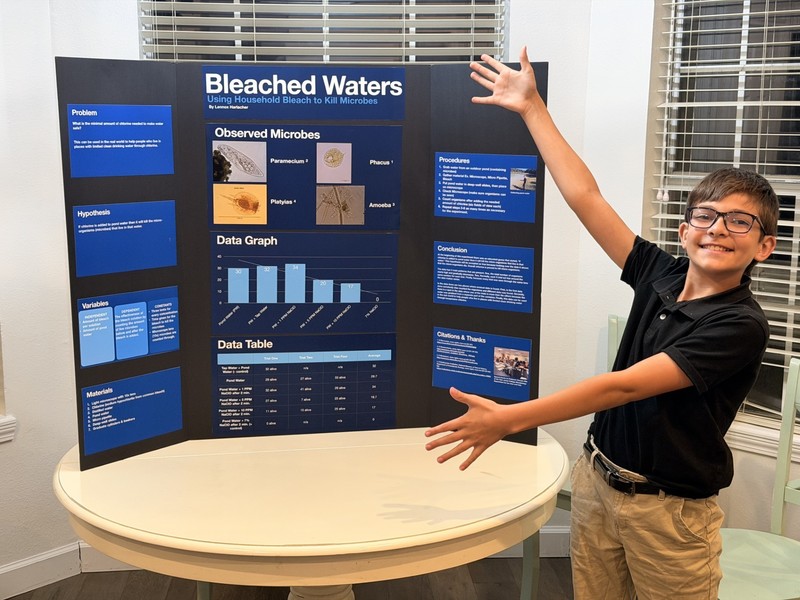 teen boy standing in front of trifold board on a table