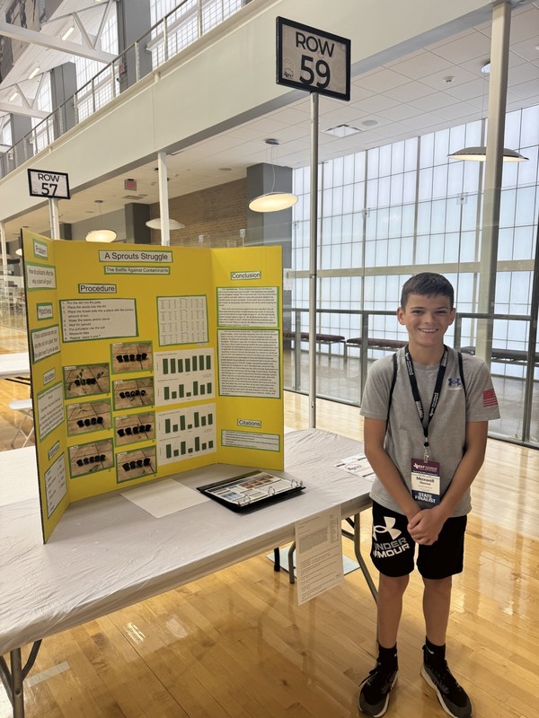 teen boy standing in front of trifold board on a table