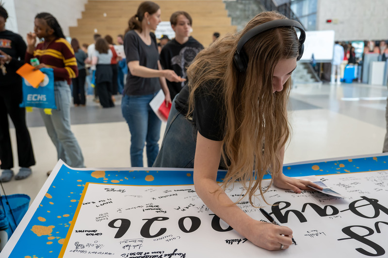 teen girl signing name on a poster