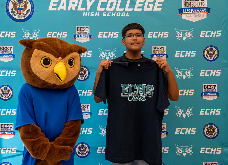 teen boy standing next to owl mascot