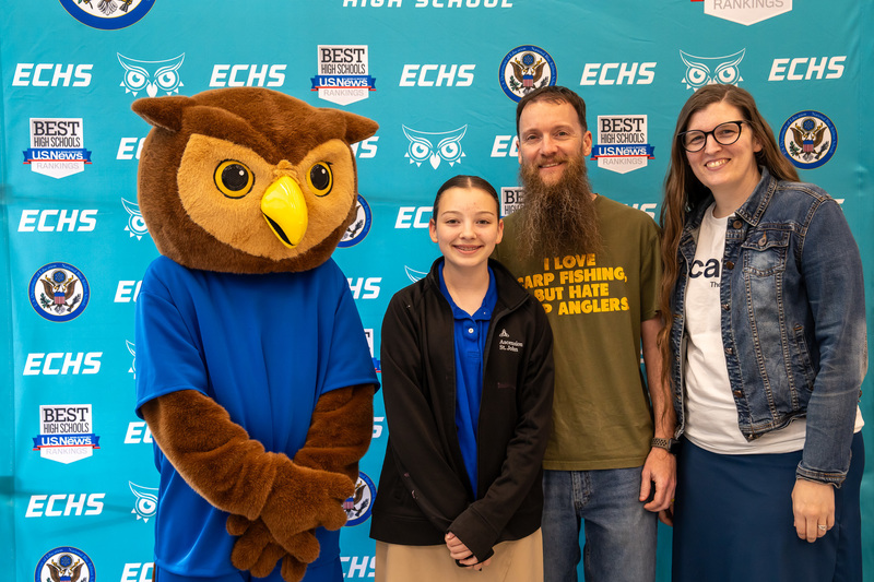 teen girl and parents standing next to owl mascot