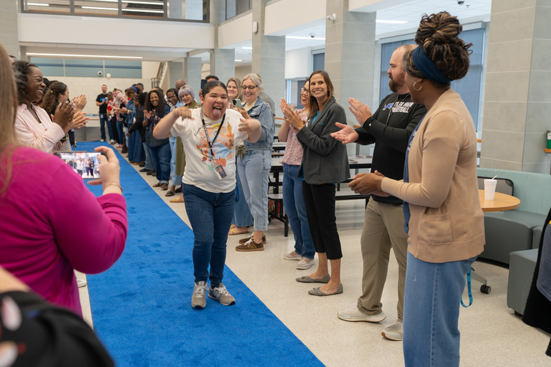 teen girl walking down blue carpet high-fiving people