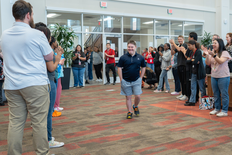 teen boy walking into library full of people