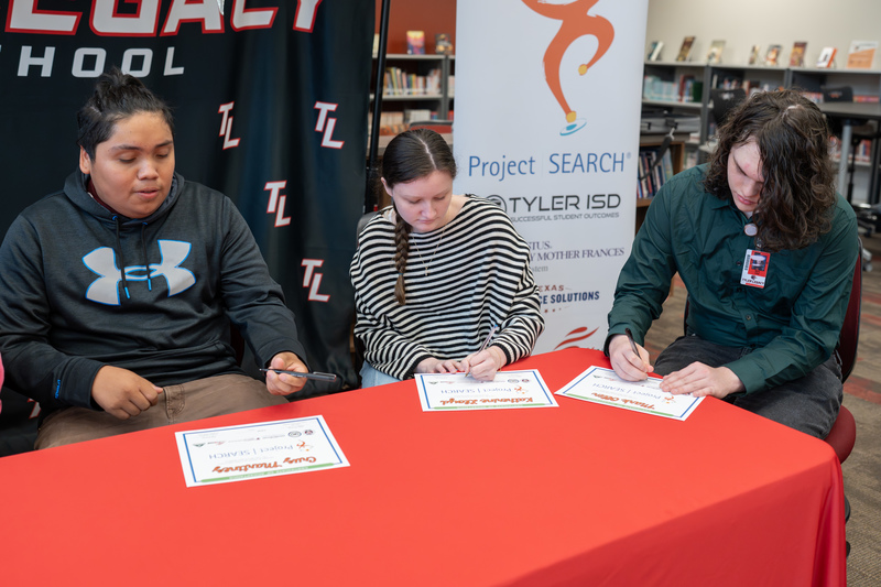teens signing papers at table