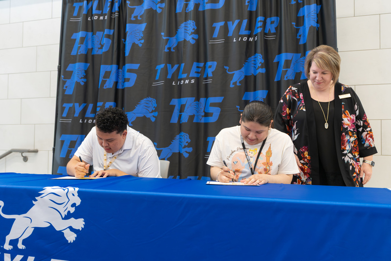 teens signing papers at table