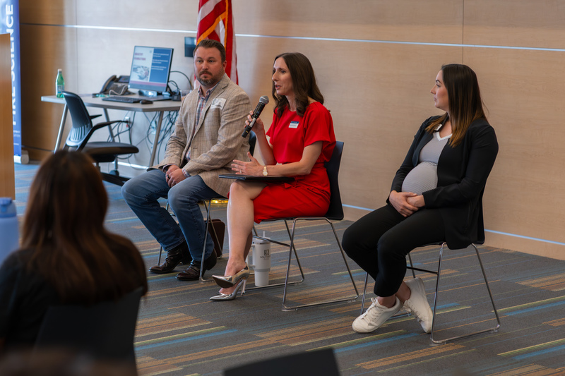 man and two women sitting at front of room talking to teens