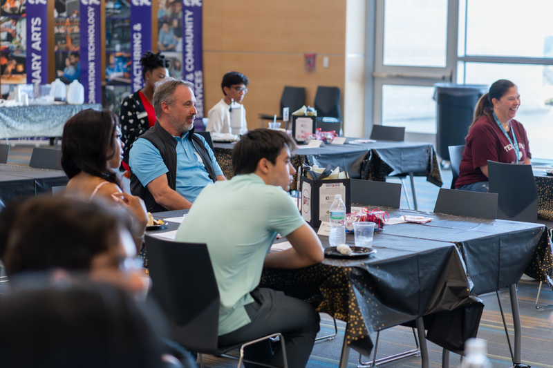 people sitting at table listening to speaker