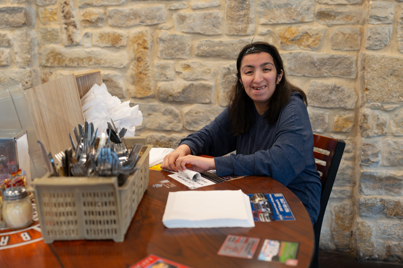 teen girl rolling silverware in napkins