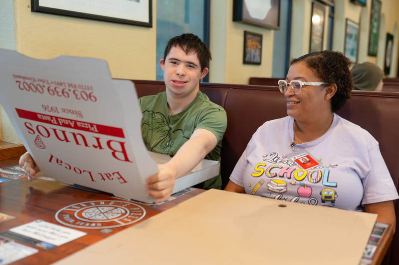 teen boy folding pizza box in a booth