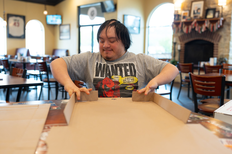 teen folding pizza box at a table
