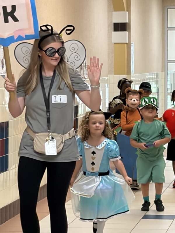teacher and students in letter costumes walking hallway 