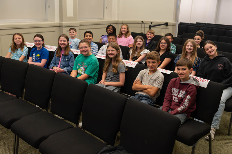 elementary age kids sitting in chairs in a courtroom