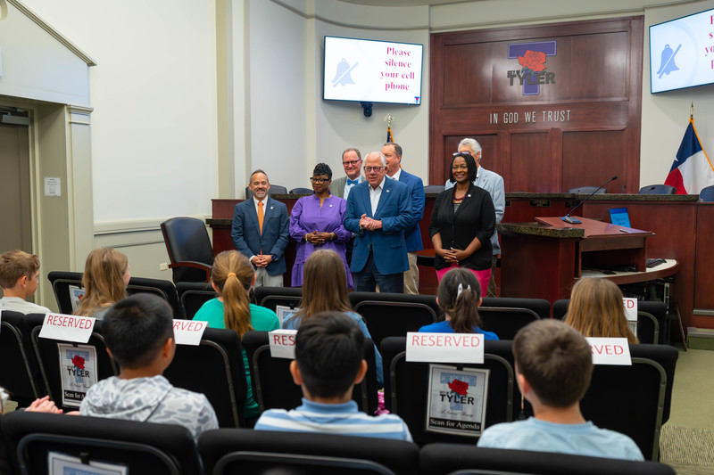 men and women standing in front of elementary age kids sitting in chairs in a courtroom