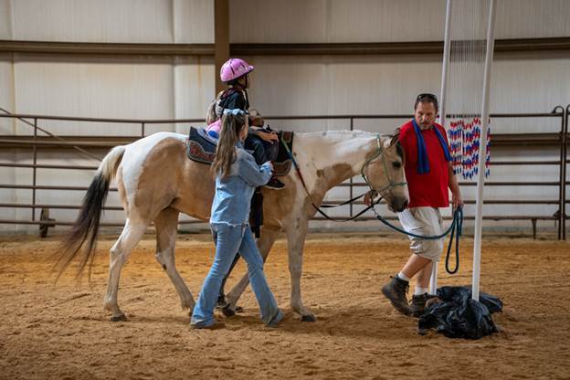elementary age girl riding horse with two women and a man walking next to them
