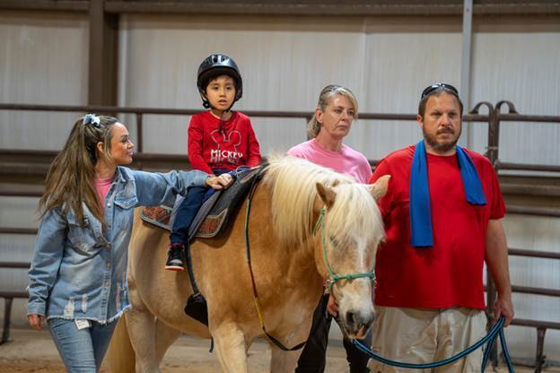 elementary age boy riding horse with two women and a man walking next to them