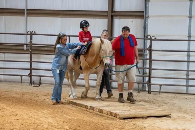 elementary age boy riding horse with two women and a man walking next to them