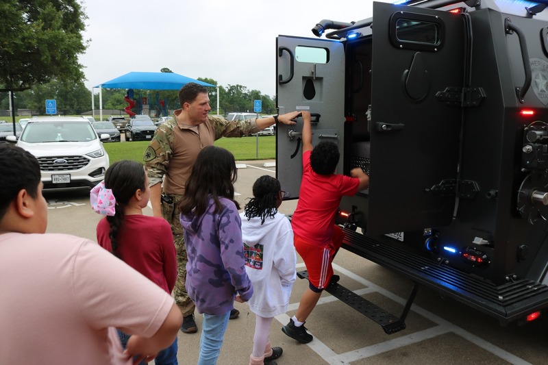 man helping kids get into a SWAT vehicle