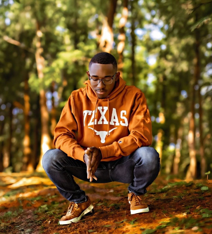 teen boy wearing UT sweatshirt squatting in woods
