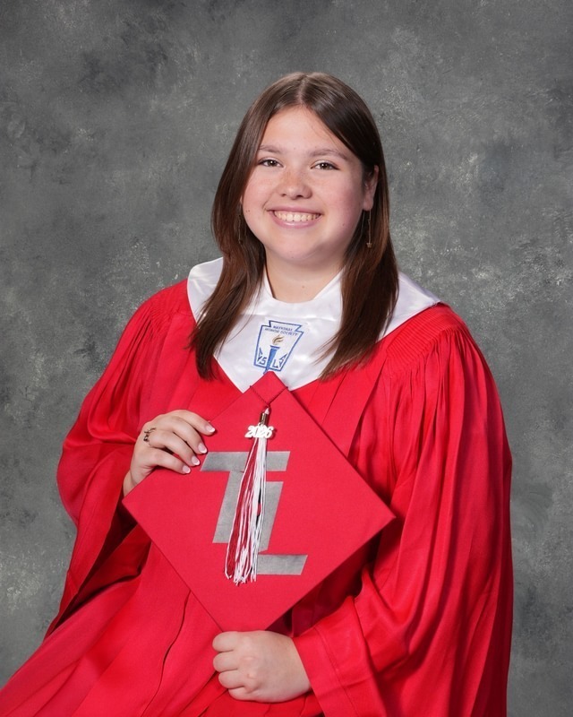 teen girl wearing red graduation gown holding her graduation cap