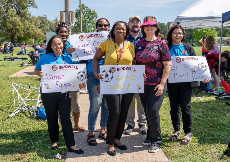 men and women on soccer field holding signs