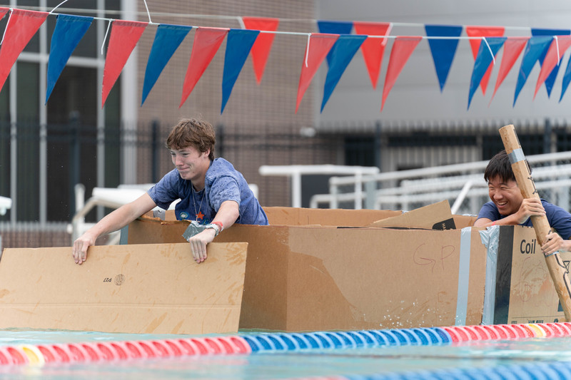 two boys in cardboard boat racing to finish line