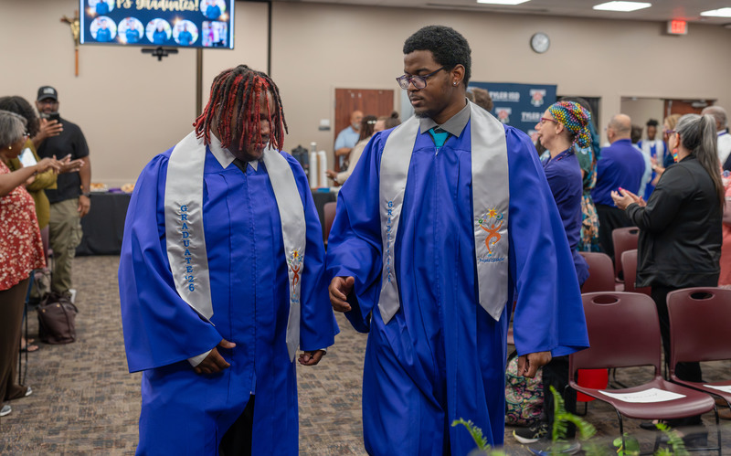 two teen boys in blue graduation gowns walking together