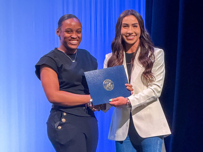 woman handing certificate to teen girl
