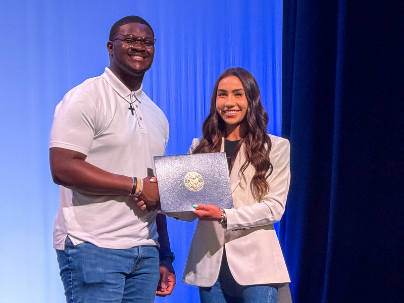 woman handing certificate to teen boy