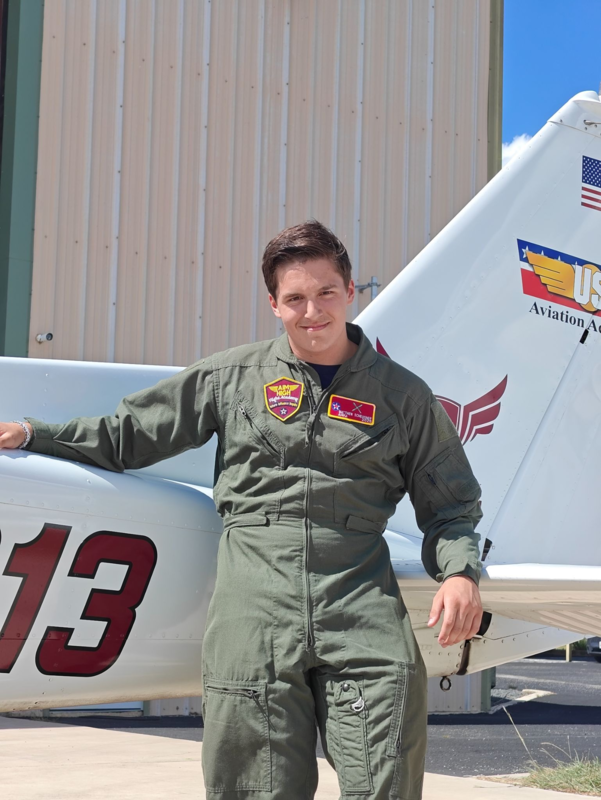 teen boy in aviation suit standing by tail of airplane