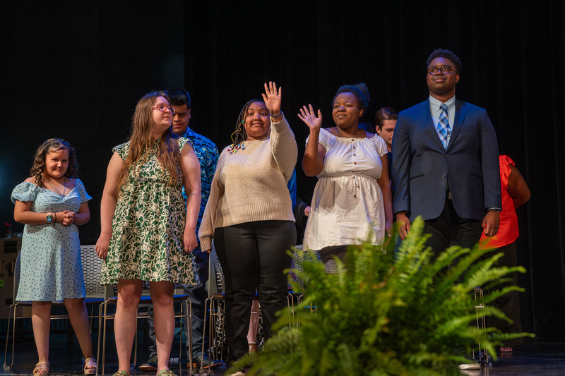 teen boys and girls on stage waving at crowd