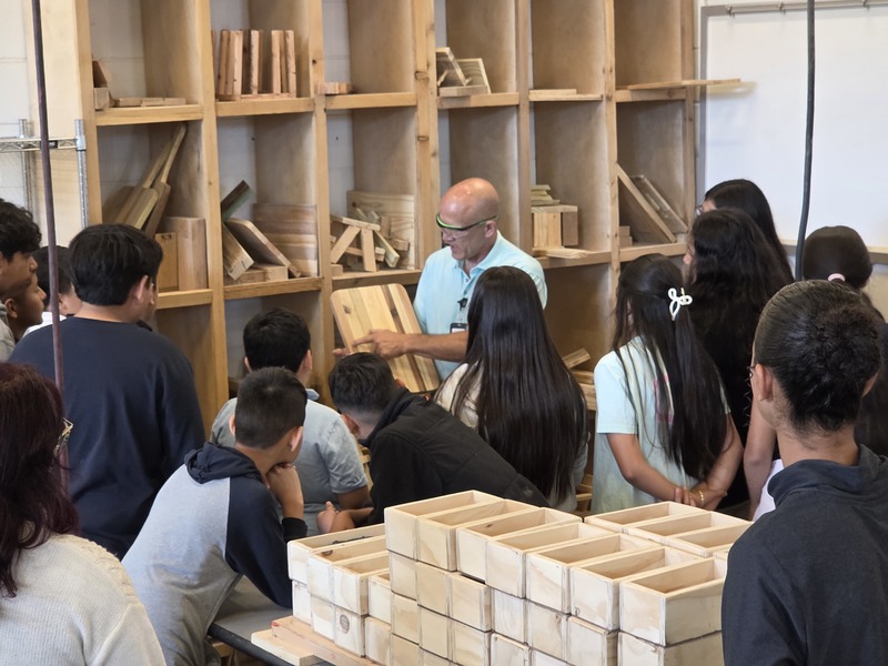 man showing cutting board to elementary kids