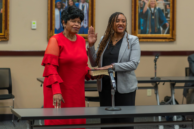 woman taking oath of office as another woman holds the Bible for him to place her hand on