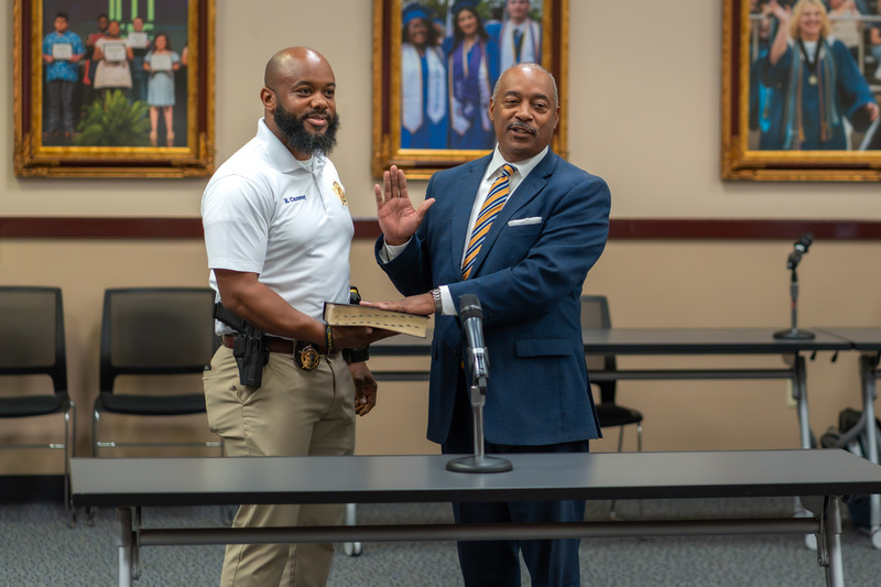 man taking oath of office as another man holds the Bible for him to place his hand on