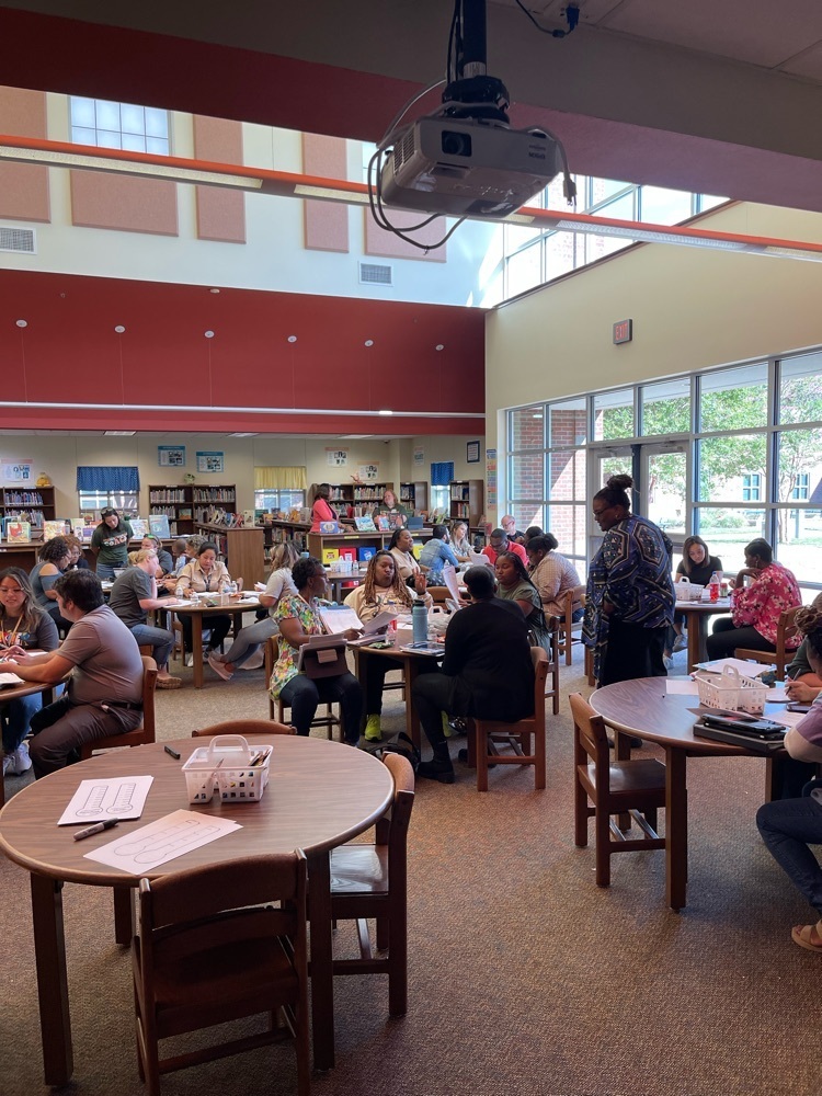 teachers in the library sitting at round tables 